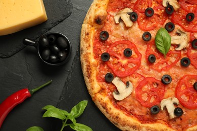 Delicious pizza with tomatoes, mushrooms, olives and basil on black textured table, flat lay