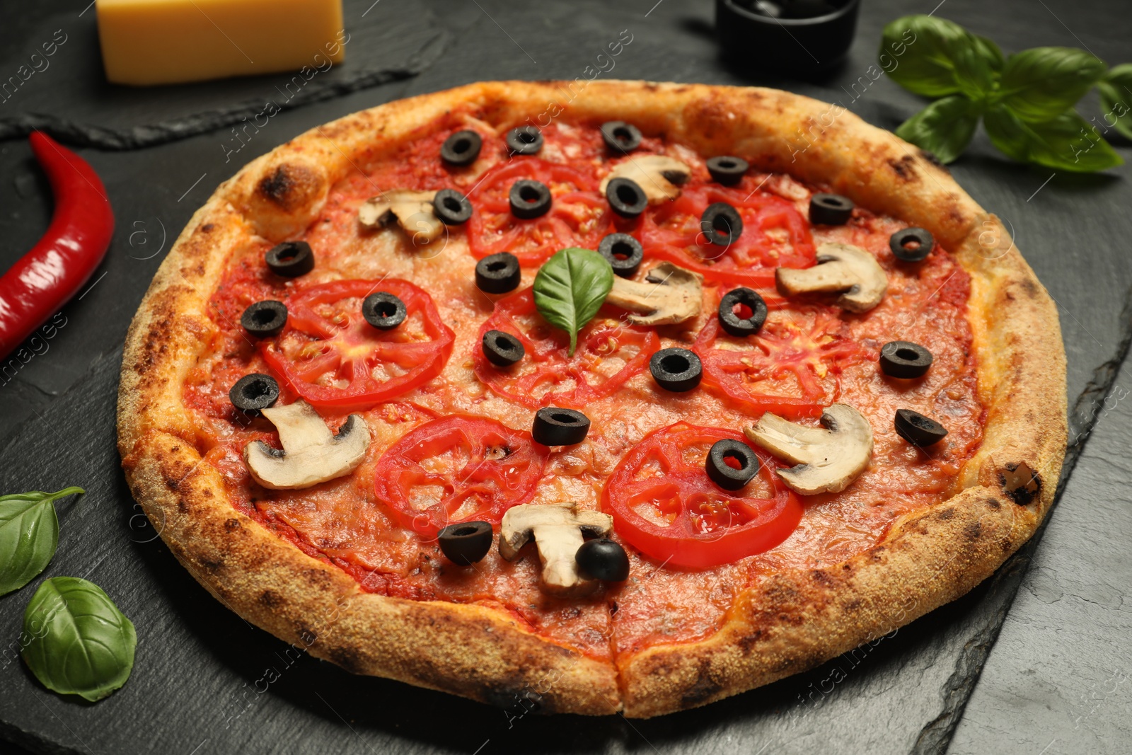 Photo of Delicious pizza with tomatoes, mushrooms, olives and basil on black table, closeup