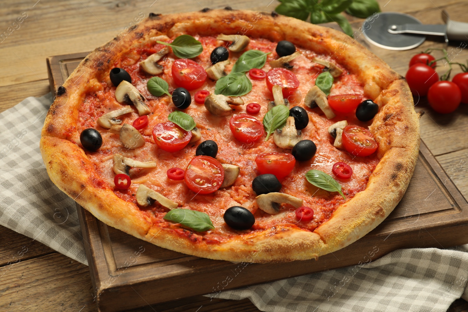 Photo of Delicious pizza with tomatoes, mushrooms, black olives and basil on wooden table, closeup