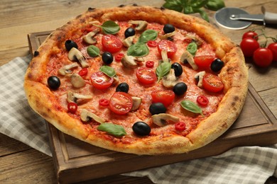 Photo of Delicious pizza with tomatoes, mushrooms, black olives and basil on wooden table, closeup