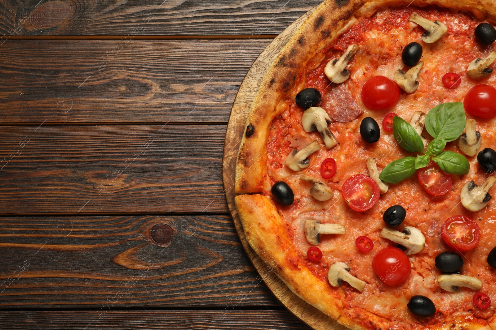 Photo of Delicious pizza with tomatoes, mushrooms, black olives and basil on wooden table, top view. Space for text