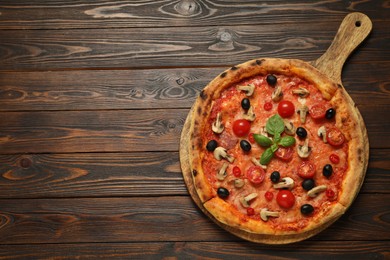 Delicious pizza with tomatoes, mushrooms, black olives and basil on wooden table, top view. Space for text