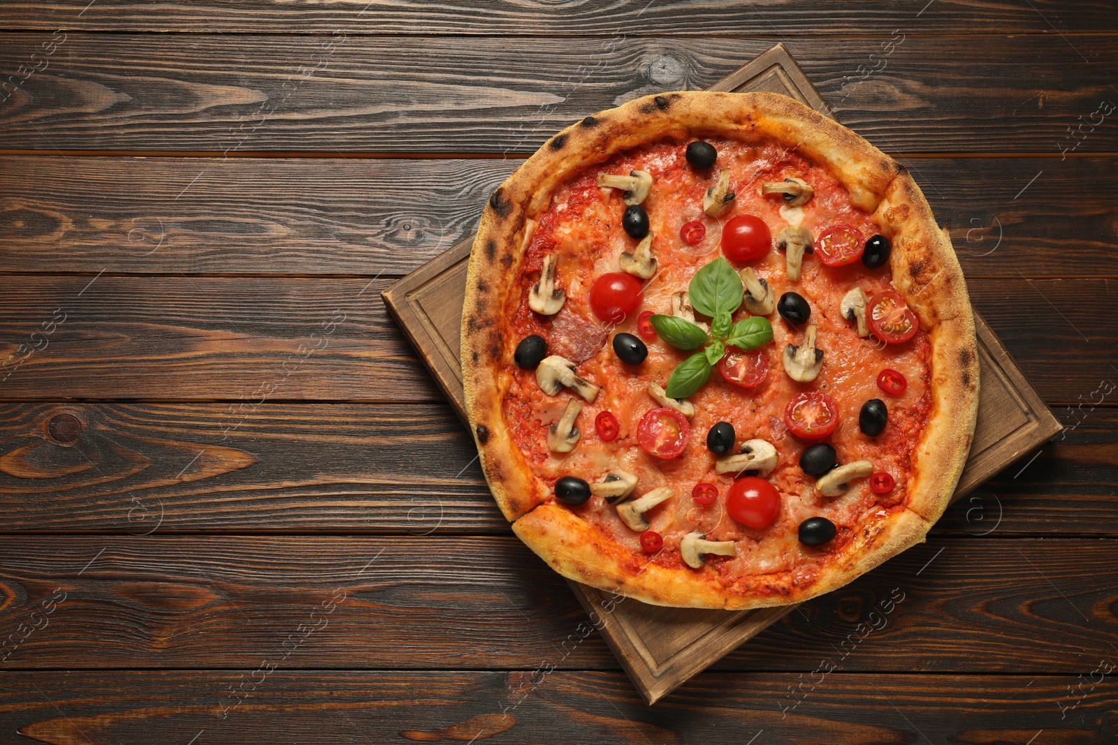 Photo of Delicious pizza with tomatoes, mushrooms, black olives and basil on wooden table, top view. Space for text