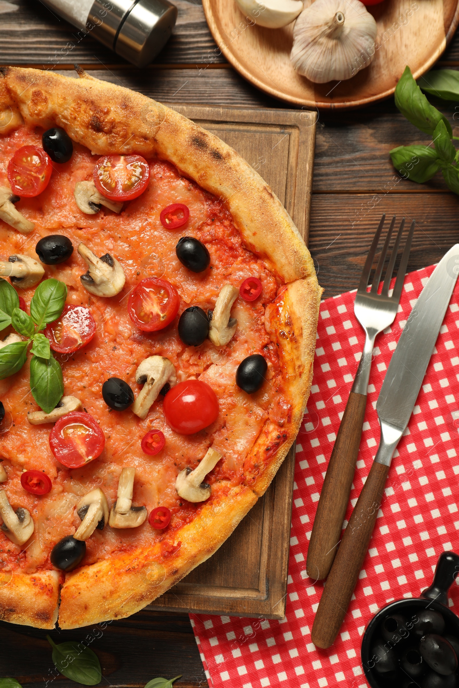 Photo of Delicious pizza with tomatoes, mushrooms, black olives and basil served on wooden table, flat lay