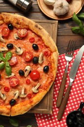 Delicious pizza with tomatoes, mushrooms, black olives and basil served on wooden table, flat lay