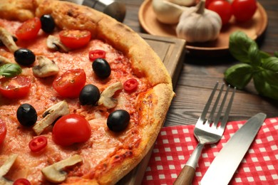 Photo of Delicious pizza with tomatoes, mushrooms and black olives served on wooden table, closeup