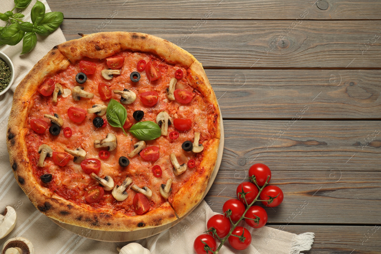 Photo of Delicious pizza with tomatoes, mushrooms, black olives and basil on wooden table, flat lay. Space for text