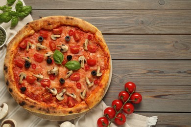 Delicious pizza with tomatoes, mushrooms, black olives and basil on wooden table, flat lay. Space for text