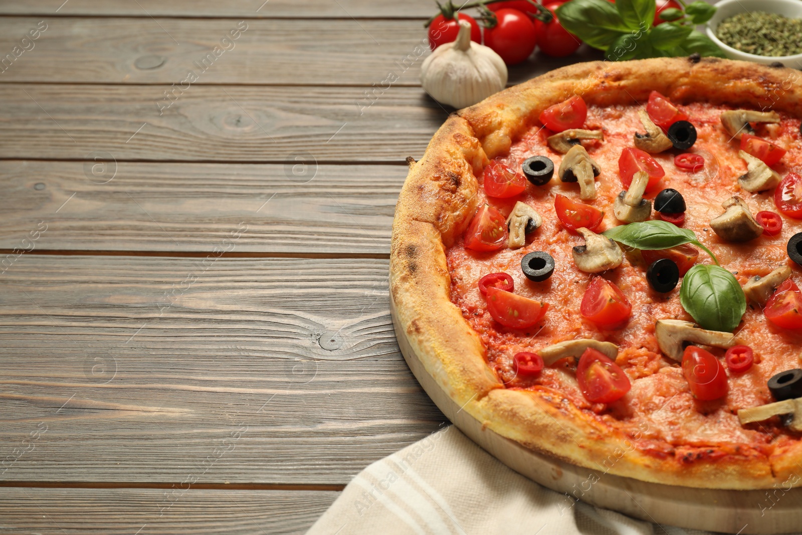 Photo of Delicious pizza with tomatoes, mushrooms, black olives and basil on wooden table, closeup. Space for text