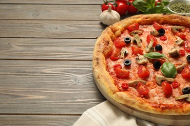 Photo of Delicious pizza with tomatoes, mushrooms, black olives and basil on wooden table, closeup. Space for text