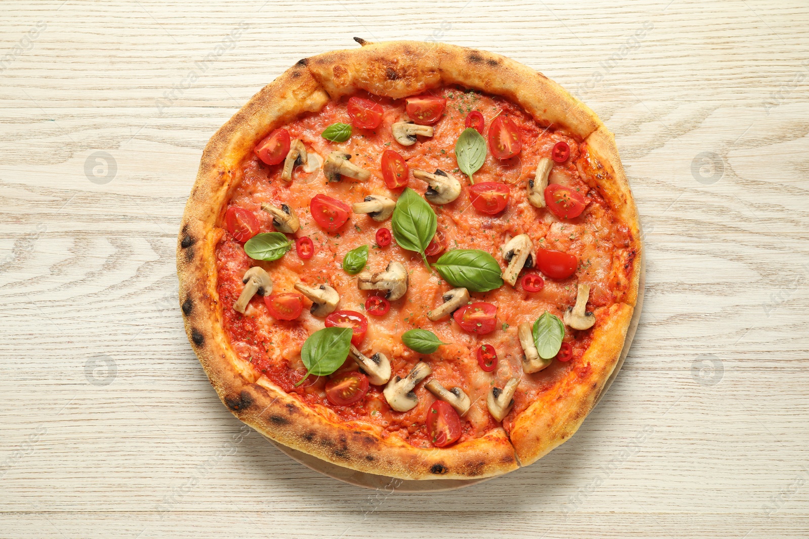 Photo of Delicious pizza with tomatoes, mushrooms and basil on wooden table, top view