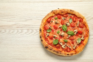 Delicious pizza with tomatoes, mushrooms and basil on wooden table, top view. Space for text