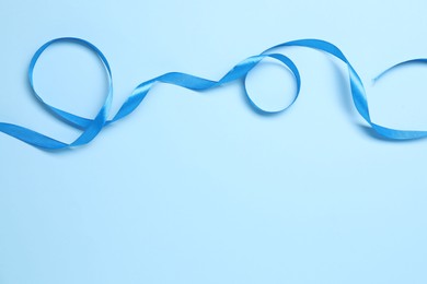 Photo of Beautiful bright ribbon on light blue background, top view. Space for text