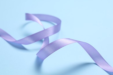 Photo of Beautiful violet ribbon on light blue background, closeup