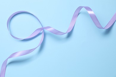 Photo of Beautiful violet ribbon on light blue background, top view