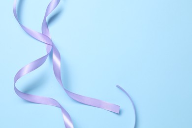 Photo of Beautiful violet ribbon on light blue background, top view. Space for text