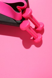 Dumbbells, fitness elastic band and yoga block on pink background, flat lay. Space for text