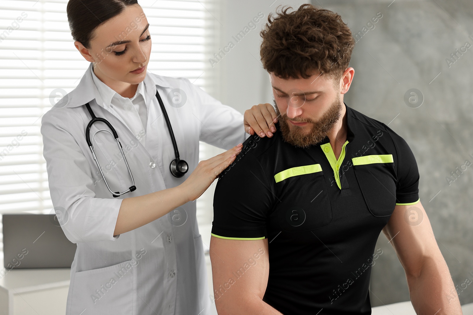 Photo of Sports injury. Doctor examining patient's shoulder in hospital