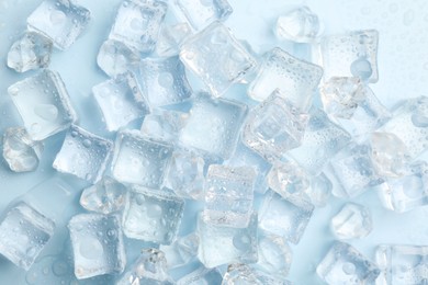 Crystal clear ice cubes on light blue background, flat lay