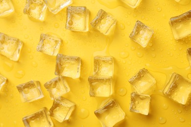 Crystal clear ice cubes on yellow background, flat lay