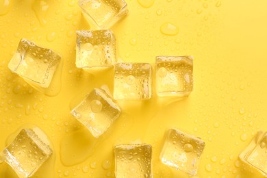 Photo of Crystal clear ice cubes on yellow background, flat lay