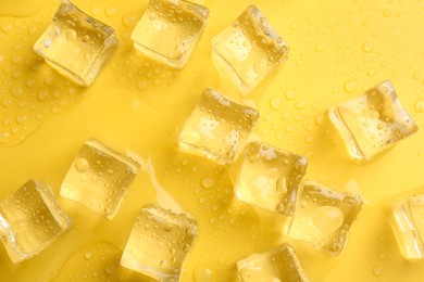 Photo of Crystal clear ice cubes on yellow background, flat lay