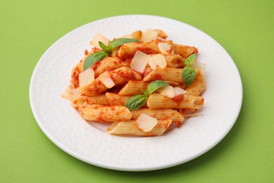 Photo of Tasty pasta with tomato sauce, cheese and basil on green background