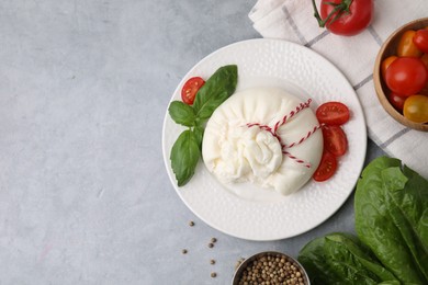 Delicious fresh burrata cheese with tomatoes and spices on grey table, flat lay. Space for text