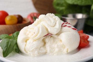 Photo of Delicious fresh burrata cheese with basil leaves on table, closeup