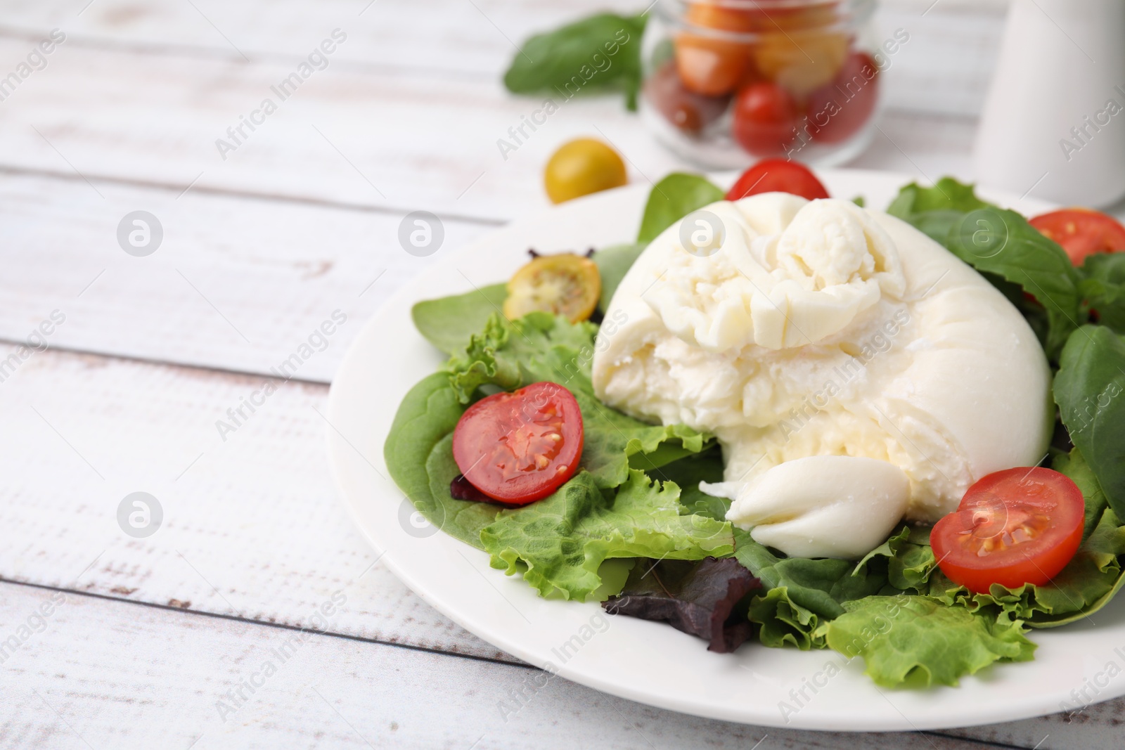 Photo of Delicious fresh burrata salad on white wooden table, closeup. Space for text