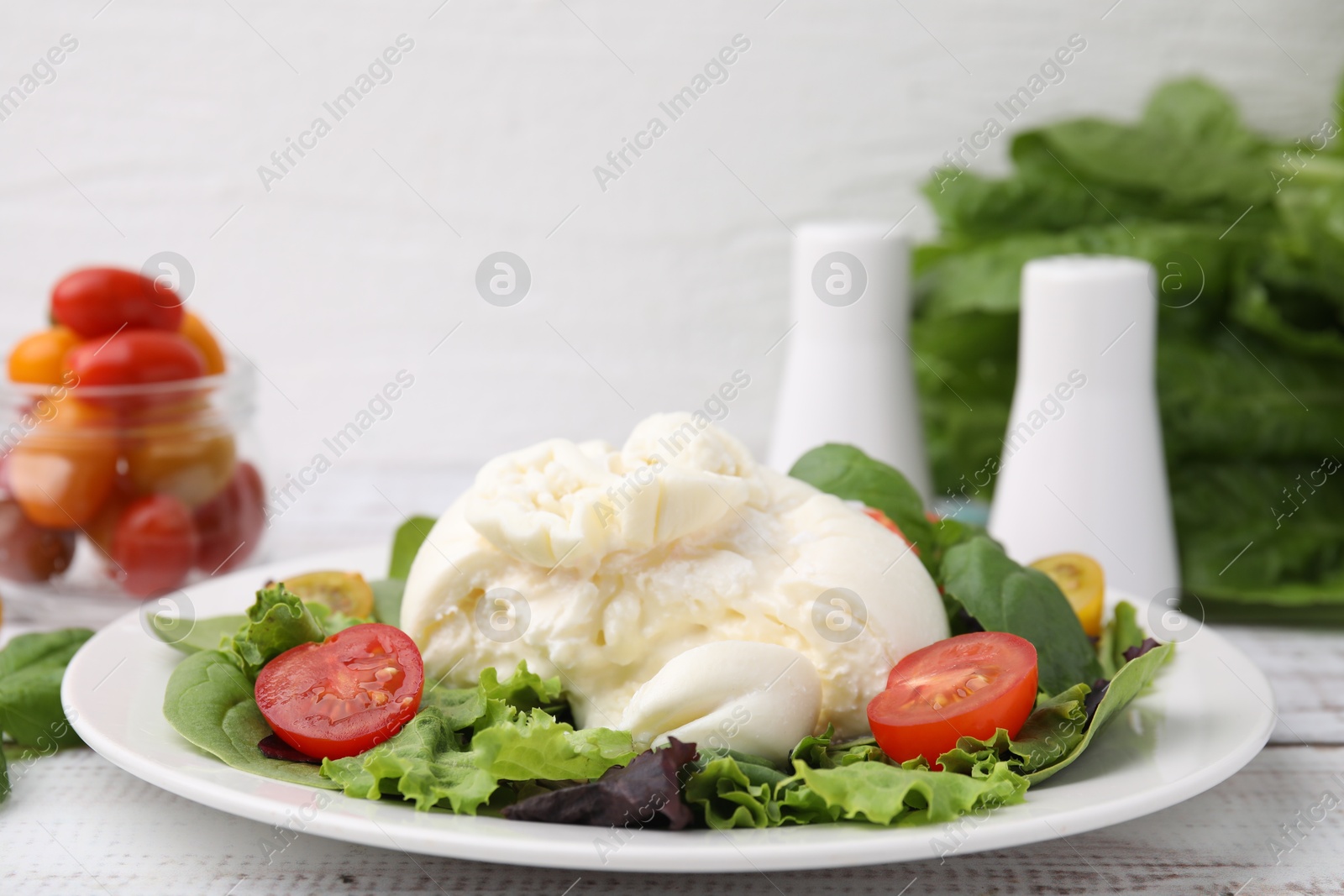 Photo of Delicious fresh burrata salad on white wooden table