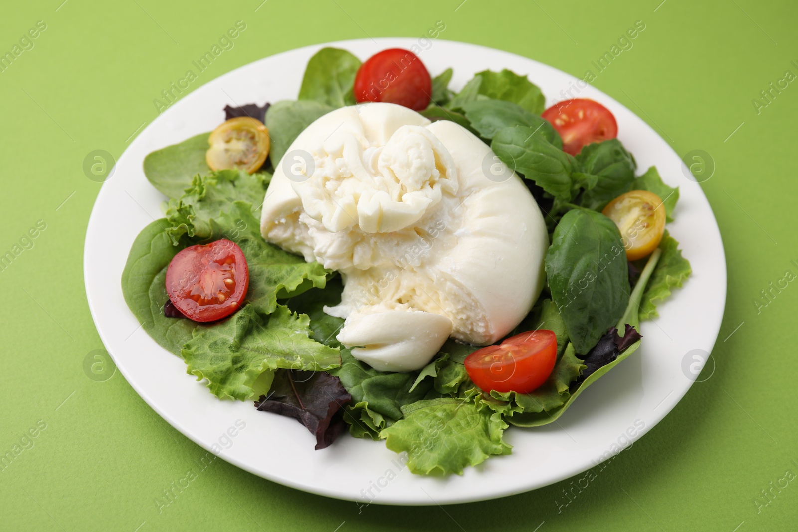 Photo of Delicious fresh burrata salad on green table