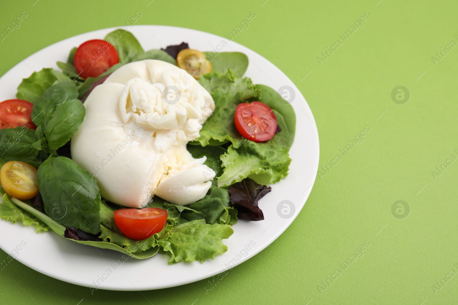 Photo of Delicious fresh burrata salad on green table. Space for text