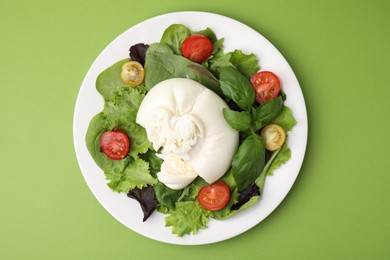 Photo of Delicious fresh burrata salad on green table, top view