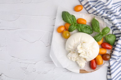 Photo of Delicious fresh burrata cheese with basil leaves and tomatoes on white textured table, flat lay. Space for text