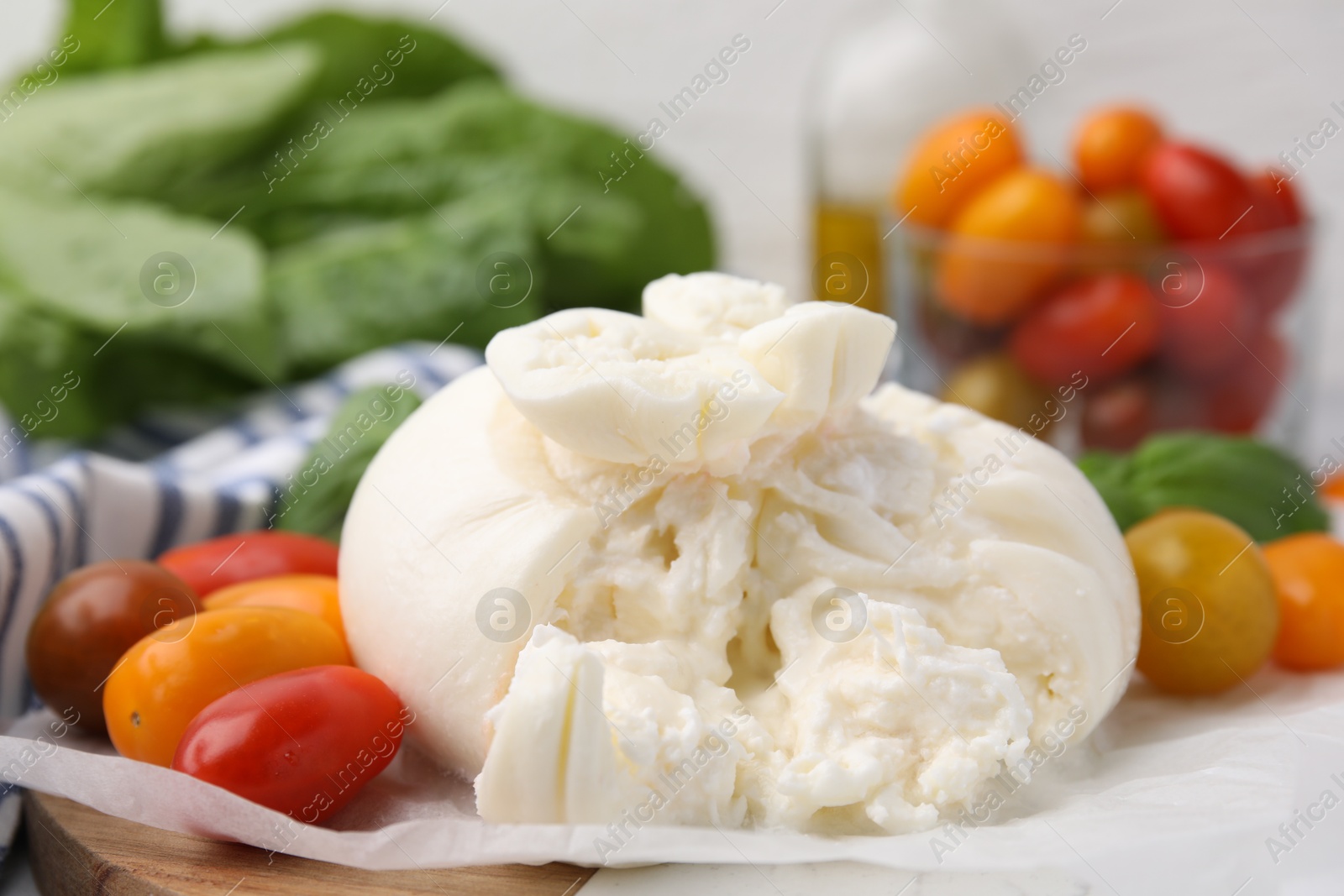 Photo of Delicious fresh burrata cheese with tomatoes on table, closeup