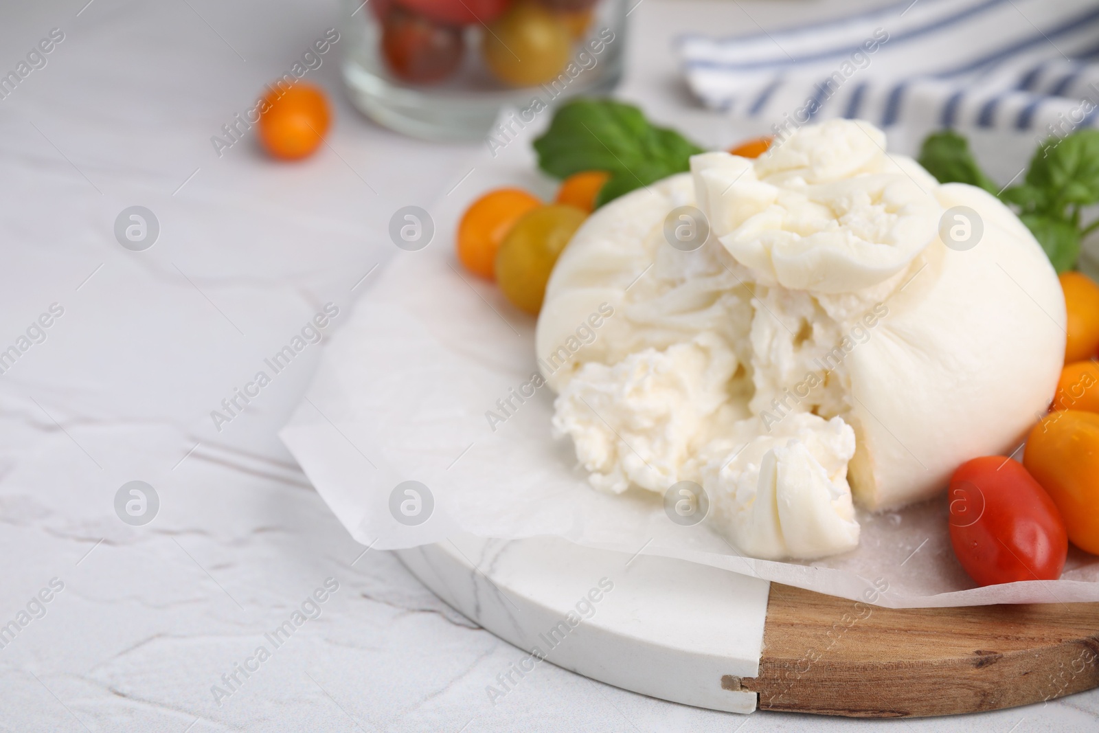 Photo of Delicious fresh burrata cheese with tomatoes on white textured table, closeup. Space for text