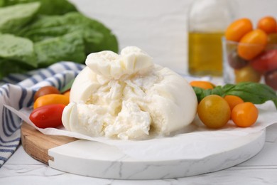 Delicious fresh burrata cheese with tomatoes on white table, closeup