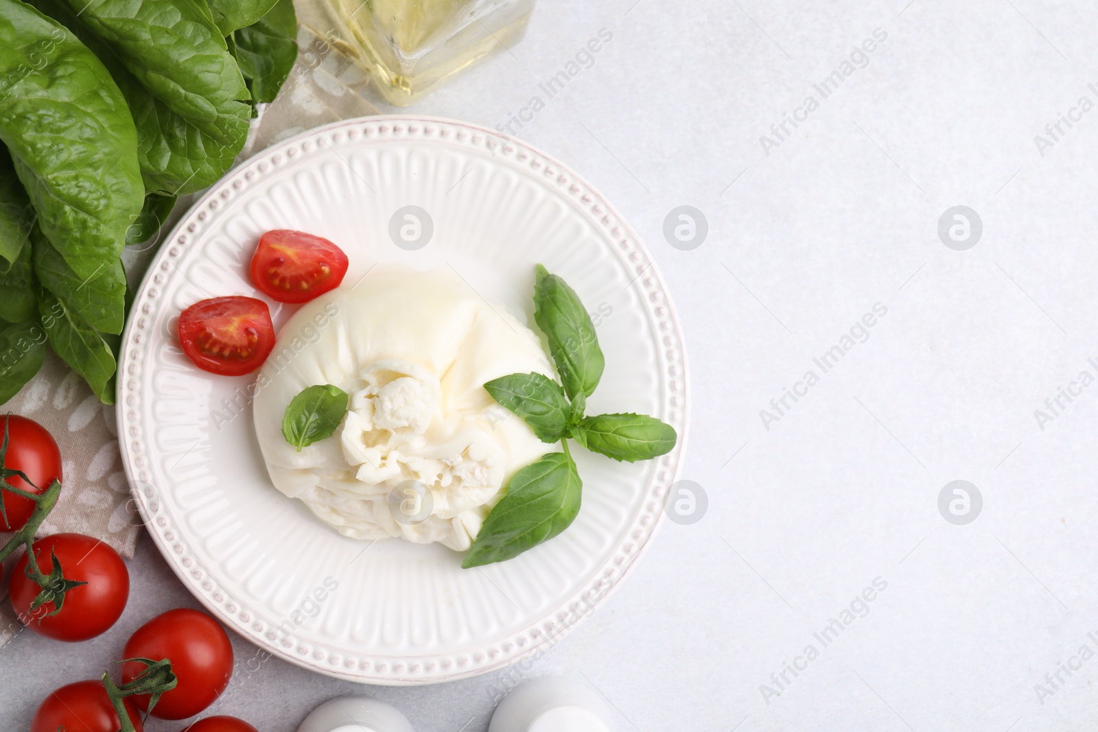 Photo of Delicious burrata cheese, tomatoes, basil and spinach on light table, flat lay. Space for text