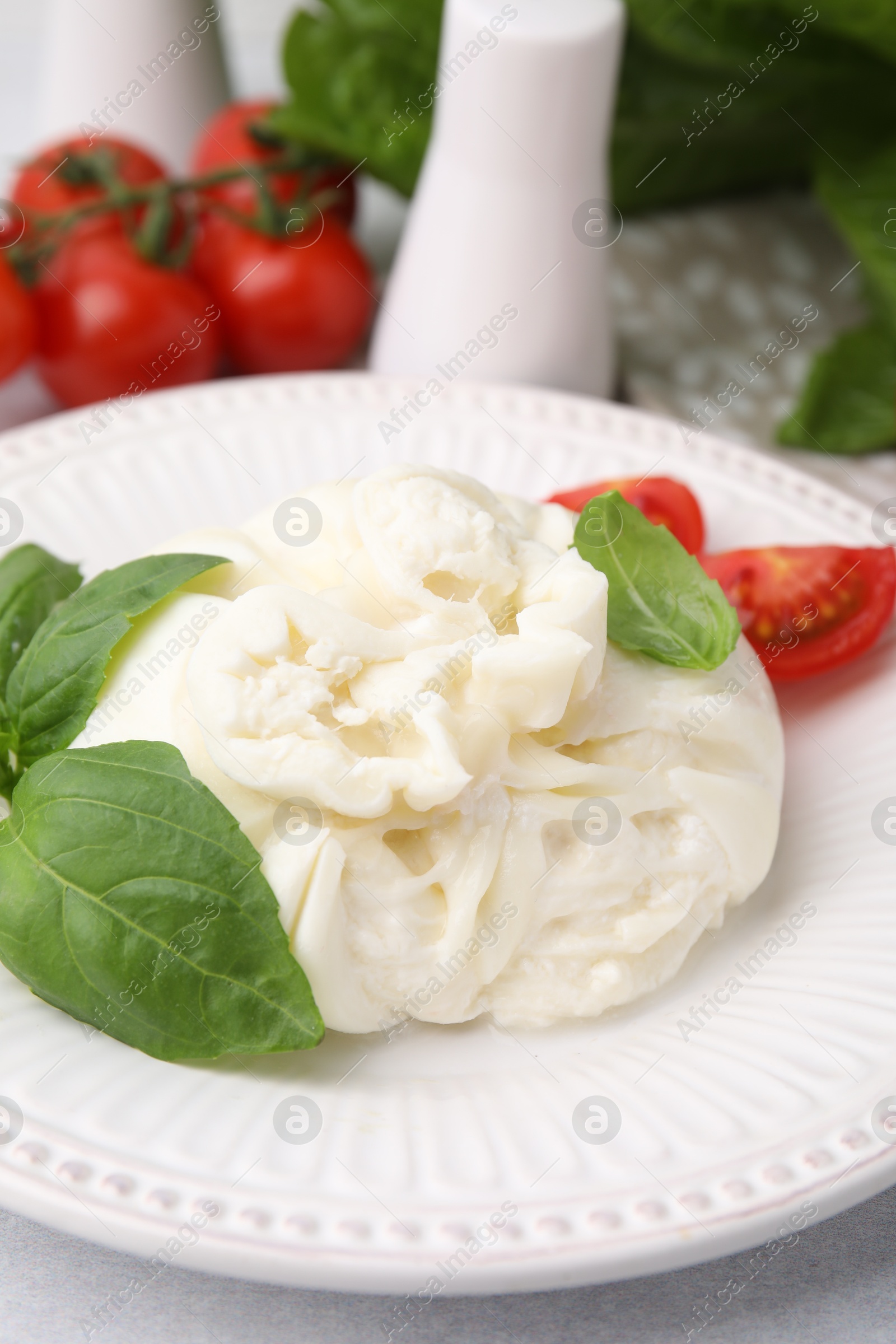 Photo of Delicious burrata cheese, tomatoes and basil on table, closeup