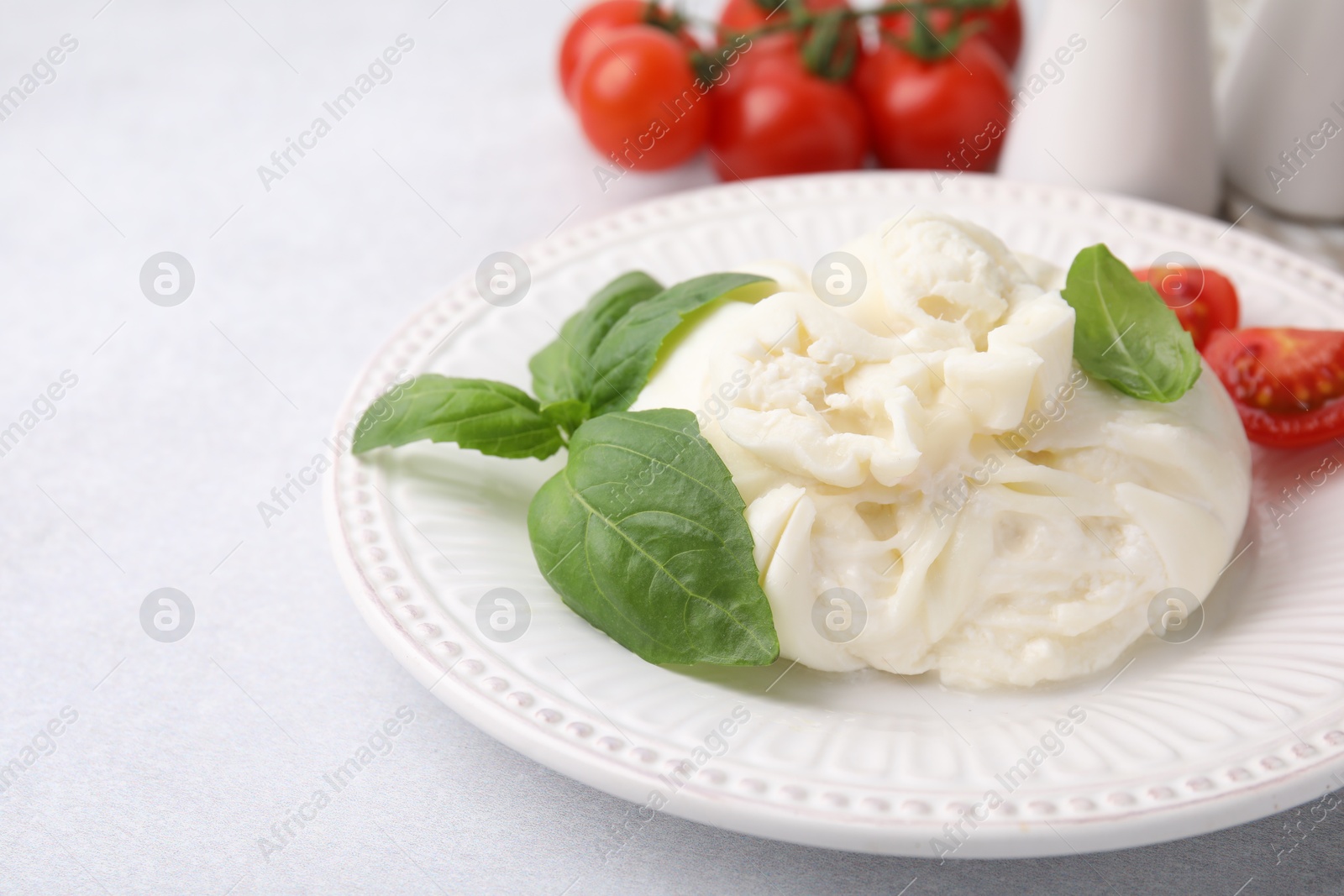 Photo of Delicious burrata cheese, tomatoes and basil on light table, closeup. Space for text