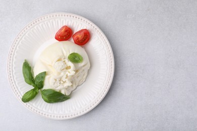 Photo of Delicious burrata cheese, tomatoes and basil on light table, top view. Space for text