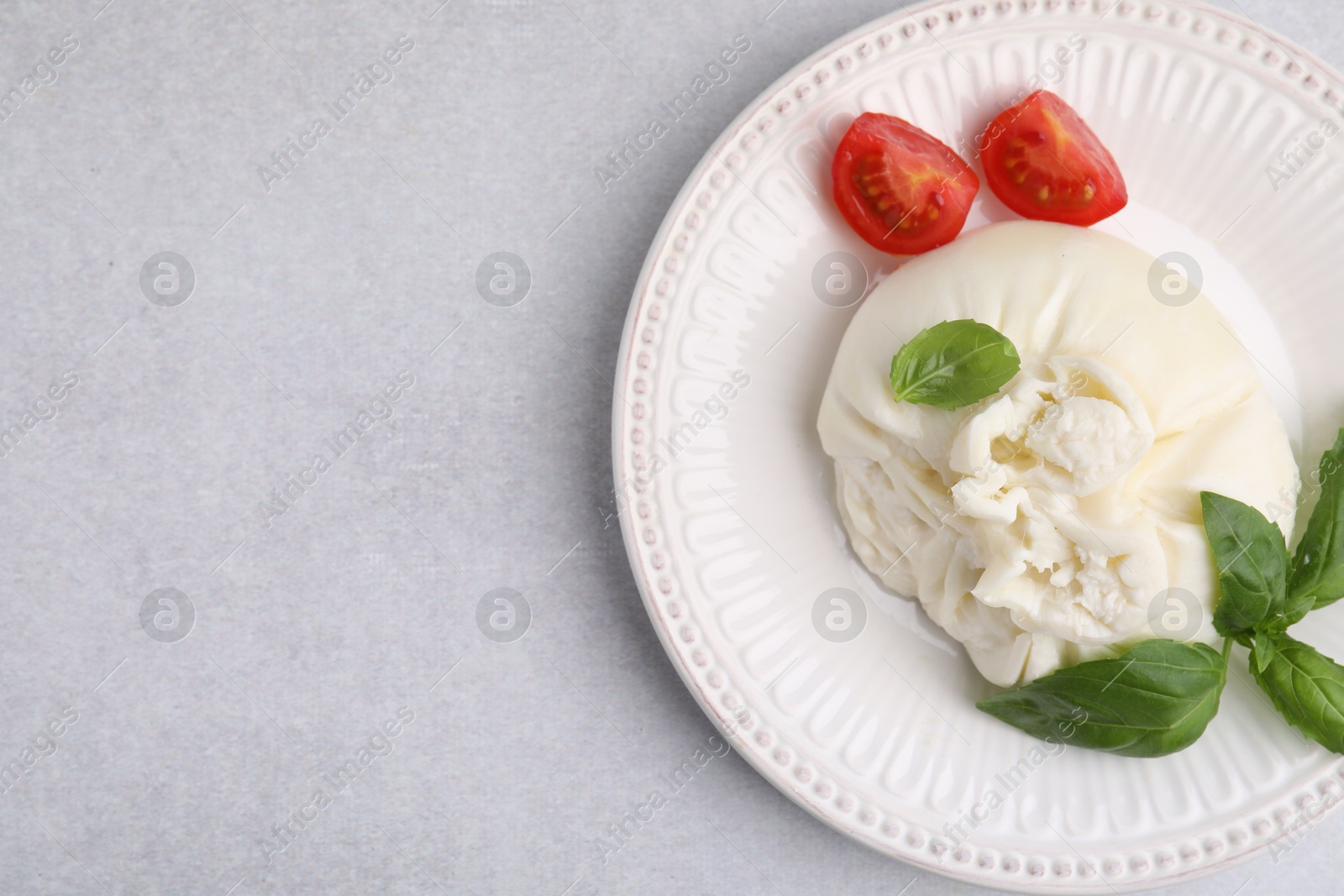 Photo of Delicious burrata cheese, tomatoes and basil on light table, top view. Space for text