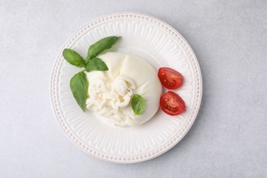 Photo of Delicious burrata cheese, tomatoes and basil on light table, top view