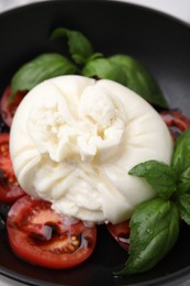 Photo of Delicious burrata cheese, tomatoes and basil in bowl, closeup