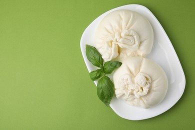 Photo of Delicious burrata cheese on green table, top view. Space for text