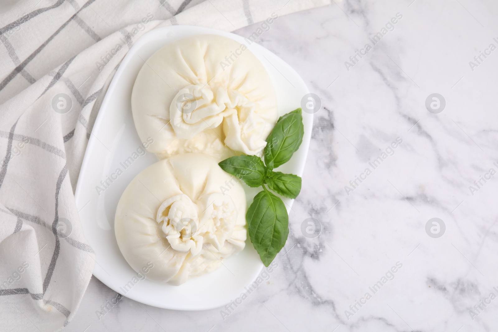 Photo of Delicious burrata cheese and basil on white marble table, top view. Space for text