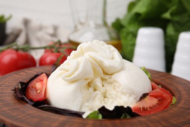 Photo of Delicious burrata salad in bowl on table, closeup