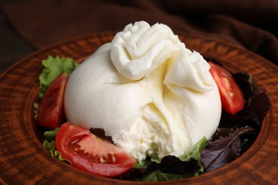 Photo of Delicious burrata salad in bowl on table, closeup