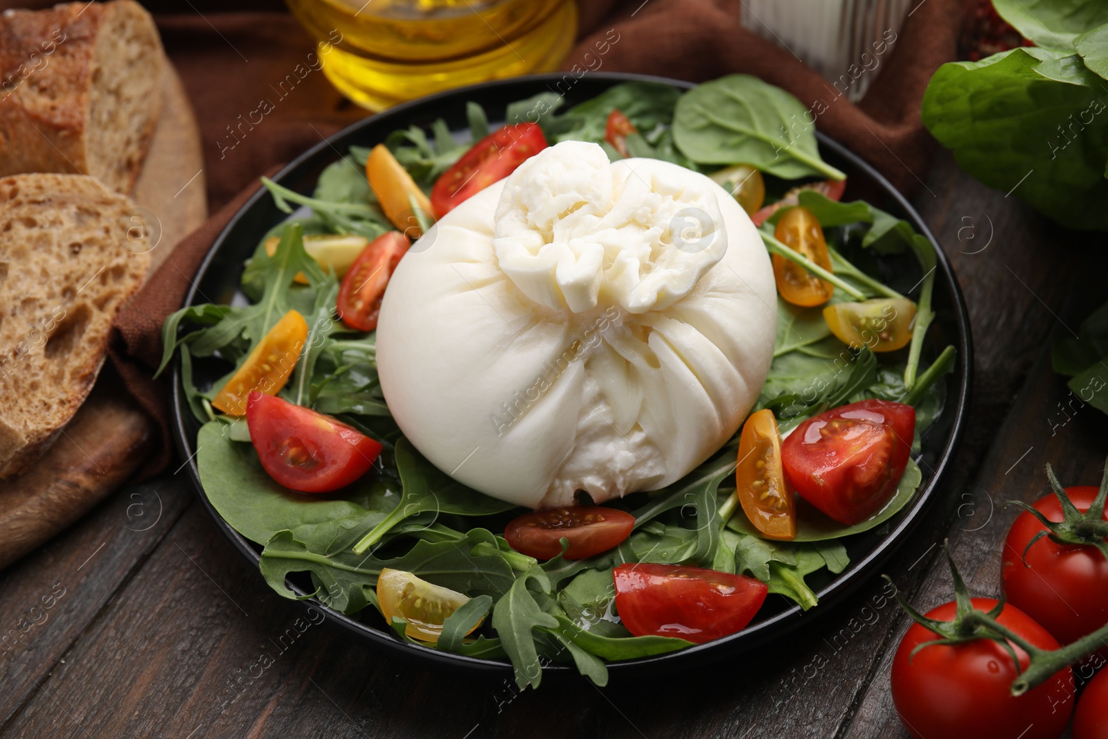 Photo of Delicious burrata salad on wooden table, closeup